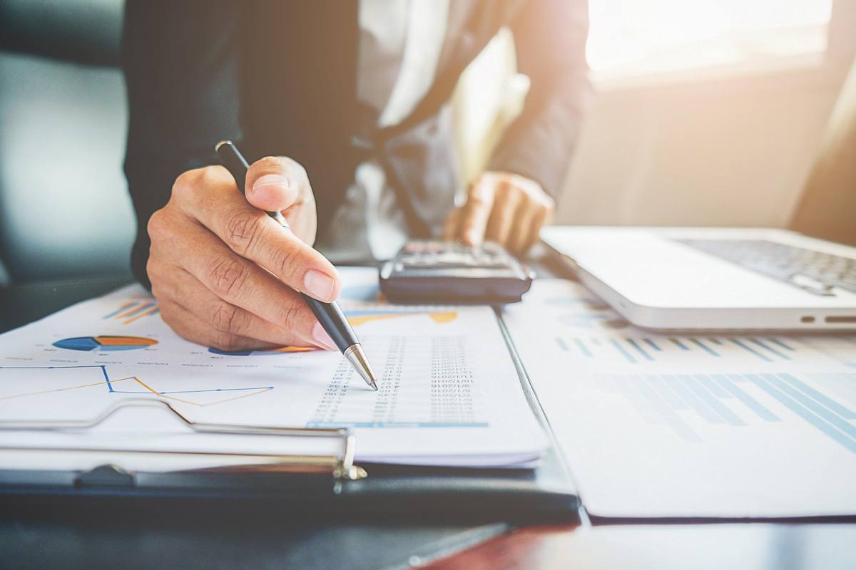 Autónomo revisando cuentas y facturas con calculadora para llevar su contabilidad básica